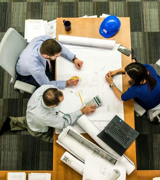 Top view of a team working on construction plans in an office setting.